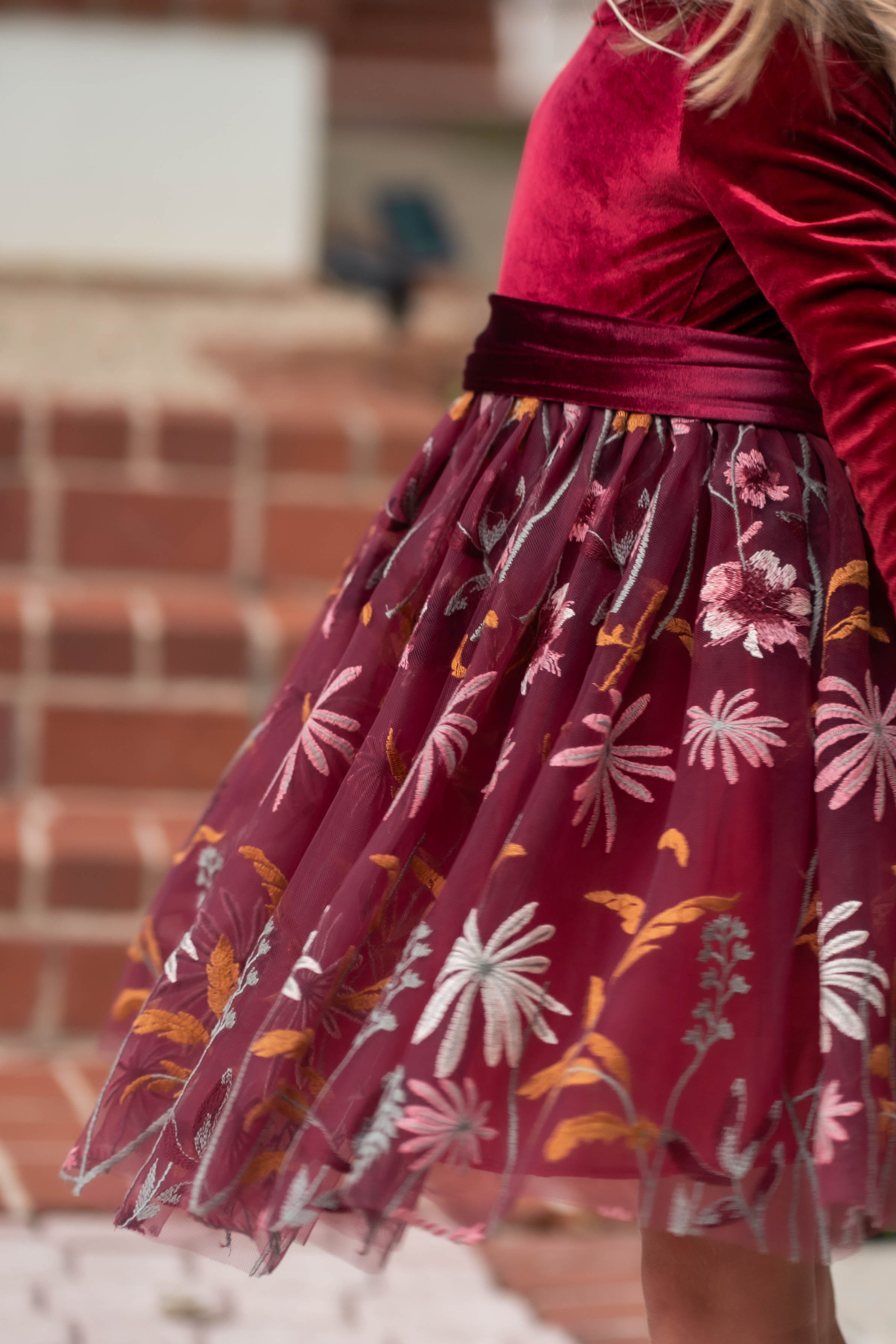 Plush velvet bodice of burgundy flower girl dress in warm glow