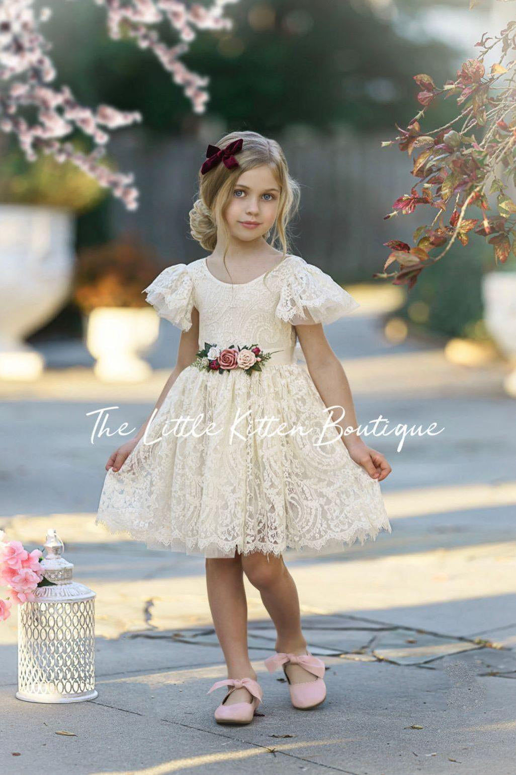 Ivory lace flower girl dress with scalloped edges and a V shaped back side. Perfect for toddlers, girls and junior bridesmaids. The lace and tulle ruffle sleeves make this girls dress whimsical. The Little Kitten Boutique offer the best flower girl dresses this season. 